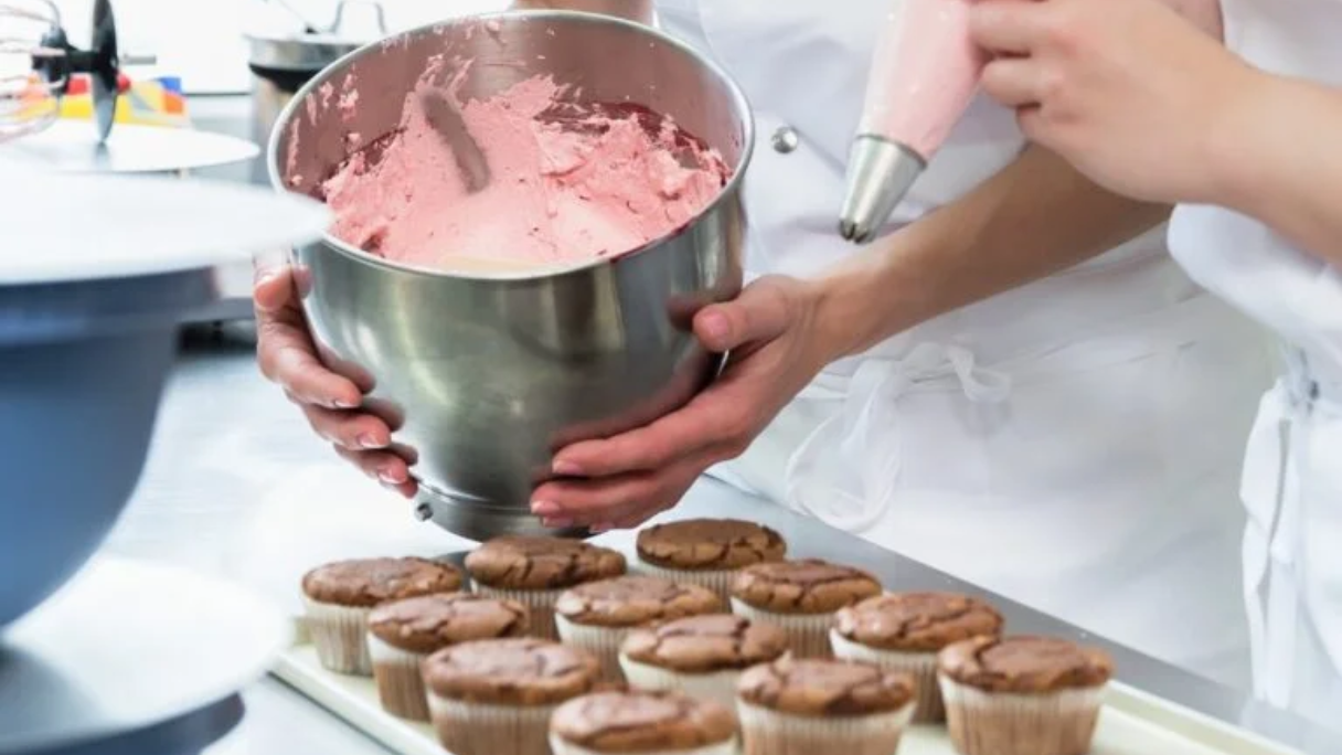Mixes pink frosting into freshly baked cupcakes.